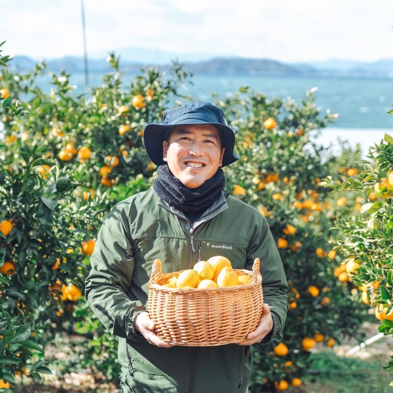 瀬戸田の柑橘畑で収穫した実をかかえる生産者